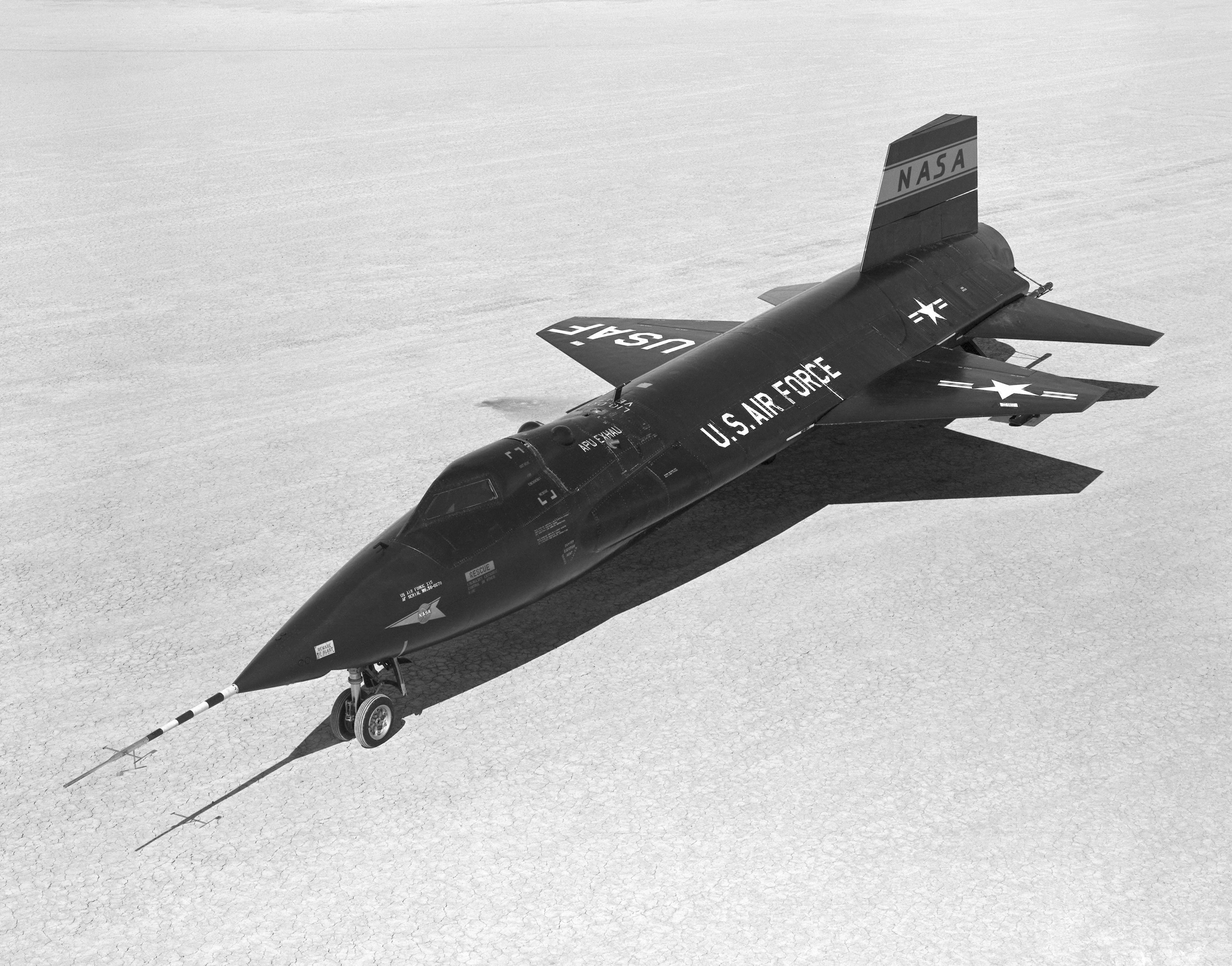 A black North American X-15 rocket plane resting on the dry lakebed at Edwards Air Force Base